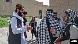 FILE - Taliban-trained suicide bomber Ismail Ashuqullah (L) speaks with Taliban's General Directorate of Intelligence (GDI) after an interview with AFP in Otarhi village in Tangi valley of Saydabad district, Maidan Wardak province, May 25, 2023. 
