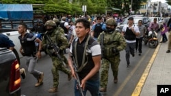 Soldiers and police provide security behind an armored vehicle as supporters of presidential candidate Daniel Noboa, of the National Democratic Action Alliance political party, attend a rally with their candidate in downtown Esmeraldas, Ecuador, Oct. 6, 2023. 