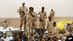 FILE - Sudanese soldiers from the Rapid Support Forces unit stand on their vehicle during a military-backed rally, in Mayo district, south of Khartoum, Sudan, June 29, 2019.