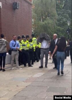 یکی از شرکت‌کنندگان در رای‌گیری حکومتی جمهوری اسلامی در لندن تلاش می‌کند چهره‌اش را پنهان کند (جمعه ۸ تیر ۱۴۰۳)