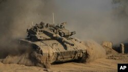 An Israeli soldier moves on the top of a tank near the Israeli-Gaza border, as seen from southern Israel, July 14, 2024. 