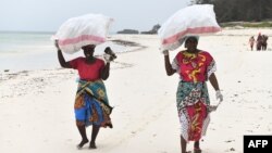 Watu waliojitolea wakiwa wamebeba mifuko iliyojaa uchafu wa plastiki katika kaunti ya Kilifi, Kenya. Picha na Simon MAINA / AFP. 