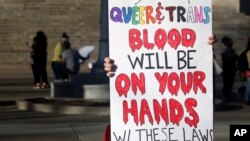 FILE - A protester outside the Kansas Statehouse holds a sign after a rally for transgender rights on the Transgender Day of Visibility, March 31, 2023, in Topeka, Kan.