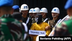 Polisi Militer mengawal satu dari enam tentara yang menjadi tersangka pembunuhan empat orang asli Papua untuk rekonstruksi di Mimika, Papua, 3 September 2022. (Foto: Sevianto Pakiding/AFP/arsip)