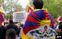 Protesters wearing Tibetan flags on their shoulders take part in a demonstration in support of members of the Tibetan and Uighur community and against the Chinese President's two-day state visit to France, at Place de la Republique in Paris, May 5, 2024.