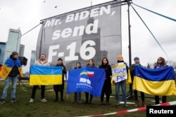 FILE - Pro-Ukraine demonstrators protest as they call on U.S. President Joe Biden to send F-16 jets to Ukraine, in Warsaw, Poland, Feb. 22, 2023.
