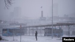 A person stands near a bus station amid heavy snowfall in Randers, Denmark, Jan. 3, 2024. 