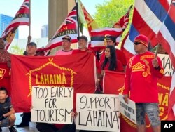 Lahaina residents and their supporters hold signs and flags at the Hawaii State Capitol in Honolulu, Oct. 3, 2023, at a news conference about a petition asking Hawaii Gov. Josh Green to delay reopening a portion of West Maui to tourism.