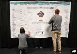 FILE - Staff members for the NCAA place the names of the teams in the Sweet 16 on a bracket in the media workroom before practices at the East Regional of the NCAA college basketball tournament in New York, March 23, 2017. (AP Photo/Julie Jacobson, File)