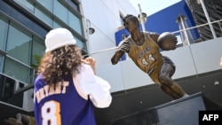 Des personnes regardent la statue de Jerry West, Los Angeles, le 12 juin 2024. 
