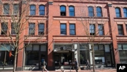 A person looks out the window as others walk by an affordable housing building March 15, 2024, in Portland, Ore.
