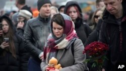 People place flowers and toys by the fence next to the Crocus City Hall, on the western edge of Moscow, March 23, 2024.