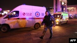 Policajac viče na prolaznike i reportere ispred hale Crocus City u predgrađu Moskve, gdje se dogodio napad. (Foto: AFP)