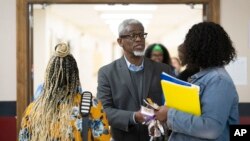 FILE - William Penn School District Superintendent Eric Becoats, center, speaks with prospective applicants during a teachers job fair at the high school's cafeteria in Lansdowne, Pa., Wednesday, May 3, 2023. (AP Photo/Matt Rourke)