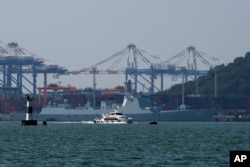 FILE - A ferry sails past a Chinese guided missile destroyer Baotou docked near a port in Xiamen in southeast China's Fujian province, Dec. 26, 2023.