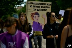 Women walk close to a banner reading "Domestic workers we do not agree with the Government", during a May Day rally in Pamplona, northern Spain, Monday, May 1, 2023.