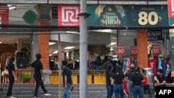 2023 年 4 月 14 日，在印度尼西亚主要岛屿爪哇岛以北的海域发生 7.0 级地震后，一家百货公司的员工在度假胜地巴厘岛登巴萨的大楼外等候。