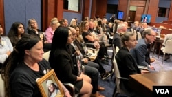 资料照片：2024年4月16日，美国芬太尼危机受害者家属在国会众议院中共问题特设委员会针对芬太尼泛滥问题召开的听证会上手拿家人的照片聆听会议。（美国之音记者李逸华摄）