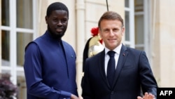 Le président sénégalais Bassirou Diomaye Faye serre la main du président français Emmanuel Macron à l'Élysée, le 20 juin 2024. AFP / Ludovic Marin