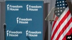 FILE - Freedom House logos are displayed on a panel behind a teleprompter next to a U.S. flag during the rights group's annual awards ceremony in Washington, May 9, 2023.