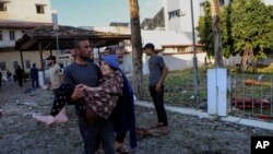 Seorang pria membawa seorang lansia keluar dari lokasi ledakan di Rumah sakit Al-Ahli di Gaza, pada 18 Oktober 2023. (Foto: AP/Abed Khaled)
