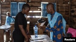 An independent National Electoral Commission agent processes a voter at the Nyabushongo Institute polling center on the second day of the Presidential election in Goma, North Kivu province of the Democratic Republic of Congo, Dec. 21, 2023.