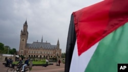 A demonstrator waves the Palestinian flag outside the Peace Palace housing the International Court of Justice in The Hague, Netherlands, May 24, 2024. The U.N. court ordered Israel to halt its military operations in Gaza.