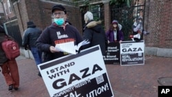George Stevens of Cambridge, Mass., hands out leaflets to passers-by near an entrance to Harvard University, Dec. 12, 2023, in Cambridge, while joining with pro-Palestinian demonstrators during a protest held to call for an end to the war in Gaza.