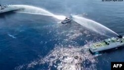 Kapal Penjaga Pantai Filipina BRP Bagacay (tengah) terkena meriam air dari kapal penjaga pantai China di dekat perairan Scarborough yang dikuasai China di perairan sengketa Laut China Selatan. (Foto: via AFP)