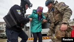 A police officer and a volunteer help a Vovchansk resident evacuate to Kharkiv due to Russian military strikes near the town of Vovchansk, in Ukraine's Kharkiv region, May 17 , 2024.