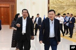 នាយករដ្ឋមន្ត្រីកម្ពុជា លោក ហ៊ុន សែន ដើរជាមួយអតីតនាយករដ្ឋមន្ត្រីថៃ លោក Thanksin Shinawatra ក្នុងជំនួបមួយនៅគេហដ្ឋានរបស់លោក ហ៊ុន សែន នៅទីក្រុងតាខ្មៅ ខេត្តកណ្តាល កាលពីថ្ងៃទី ៥ ខែសីហា ឆ្នាំ ២០២៣។ (Cambodia's Prime Minister Telegram via AP)