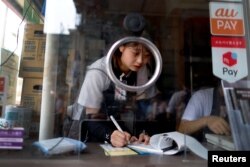 Novice rickshaw puller Riho Arai, 19, takes a break inside the ticket booth during work, at the Asakusa district in Tokyo, Japan, June 18, 2023.