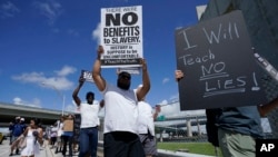 People carry signs during the "Teach No Lies" march to the School Board of Miami-Dade County to protest Florida's new standards for teaching Black history, which have come under intense criticism for what they say about slavery, Aug. 16, 2023, in Miami.