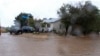 A resident checks flood waters surrounding his home during a downpour in Palmdale, California, as a tropical storm moves into the area, Aug. 20, 2023.
