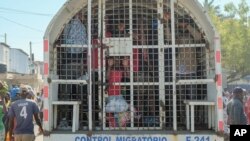 Orang-orang yang ditahan untuk dideportasi ke Haiti, berdiri di dalam truk polisi di jembatan perbatasan yang menghubungkan kota Dajabon, Republik Dominika dengan Haiti. (AP)