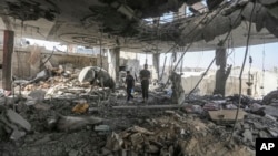 Palestinians stand in the ruins of a home after an overnight Israeli strike that killed at least two adults and five boys and girls under the age of 16 in Rafah, southern Gaza Strip, May 3, 2024.