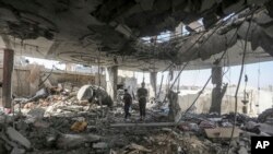 Des Palestiniens se tiennent dans les ruines d'une maison familiale, détruite par une frappe israélienne qui aa ussi tué au moins deux adultes et cinq garçons et filles de moins de 16 ans à Rafah, dans le sud de la bande de Gaza, le vendredi 3 mai 2024. (AP/Ismaël Abou Dayyah)