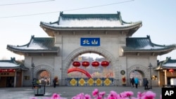 FILE - Tourists walk past a gateway with the name 'Beishan' seen at the Beishan Park in northeastern China's Jilin province, Jan. 23, 2020. Four instructors from Iowa's Cornell College teaching at Beihua University were attacked, reportedly with a knife.