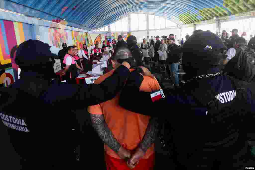 Petugas penjara mengawal seorang narapidana untuk memberikan suara selama pemungutan suara awal bagi orang-orang yang berada dalam tahanan preventif di penjara Barrientos, menjelang pemilihan umum 2 Juni, di Tlalnepantla, Meksiko, 8 Mei 2024.
