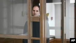 Wall Street Journal reporter Evan Gershkovich stands in a glass cage in a courtroom at the Moscow City Court, in Moscow, Russia, on Dec. 14, 2023. 