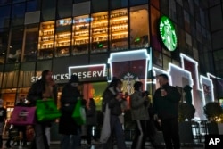 រូបឯកសារ៖ មនុស្ស​ដើរ​កាត់​ហាង​ Starbucks នៅ​ខាងក្រៅផ្សារ​ទំនើប​មួយ នៅទីក្រុងប៉េកាំង ប្រទេសចិន កាលពី​ថ្ងៃទី២៣ ខែធ្នូ ឆ្នាំ២០២៣។