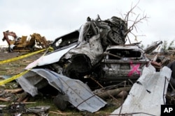Damaged cars sit piled up next to a road after a tornado in Greenfield, Iowa, May 21, 2024.