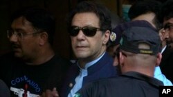 FILE - Pakistan's former Prime Minister Imran Khan is escorted by security officials as he arrives at court in Islamabad, May 12, 2023.