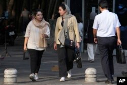 تہران میں دو خواتین سڑک پر چلتے ہوئے ، جنہوں نے سر پر دوپٹے لے رکھے ہیں ، فوٹو اے پی 5 اگست 2023