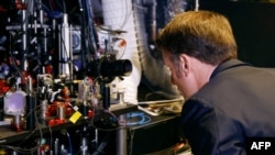 FILE - France's President Emmanuel Macron looks at a laser experimentation process during a visit to the experimental quantum physics laboratory of the University of Amsterdam, April 12, 2023.