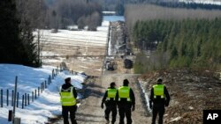 Finland's border guards walk at construction site of the border barrier fence between Finland and Russia near Pelkola border crossing point in Imatra, Finland, April 14, 2023.