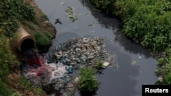FILE - Water, which has been colored by textile dye and will eventually flow through the Labandha, Turag and Buriganga rivers, is released near a paddy field in the Mawna Union area, north of Gazipur, Bangladesh, March 2, 2023.