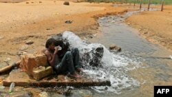 Un migrant d'origine africaine boit de l'eau à son arrivée dans une zone inhabitée près d'al-Assah à la frontière libyo-tunisienne le 30 juillet 2023.