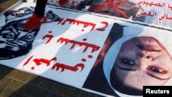 ARHIVA - Irački demonstranti hodaju preko crteža sa likom bivšeg predsednika Iraka Sadama Huseina i fotografije njegove ćerke Ragad Sadam Husein, tokom antivladinih protesta u Bagdadu, Iraj, 21. decembra 2019.