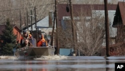 Russian Emergency Situation Ministry rescuers ride a boat to help local residents during evacuations from a flooded area in Orenburg, Russia, on April 11, 2024.